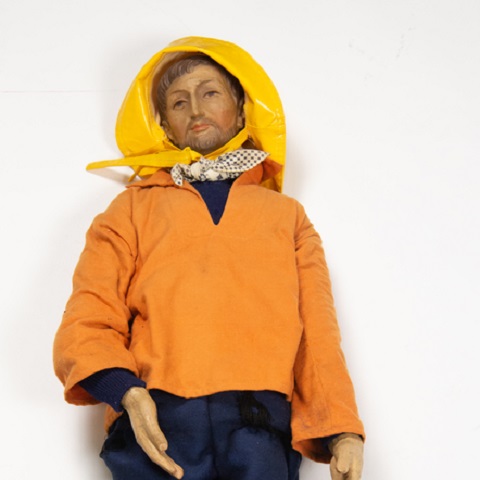 kleurenfoto van visser met gele zuidwester-hoed en werkkleding.